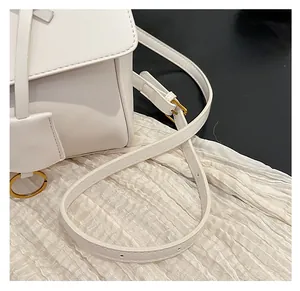 Close-up of adjustable white PU leather strap with golden metal buckle and ring details