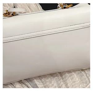 Close-up of premium white matte leather texture and golden metal hardware on tote bag