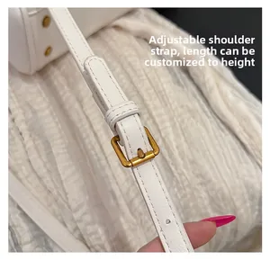 Close-up of adjustable white leather shoulder strap with gold metal buckle detail