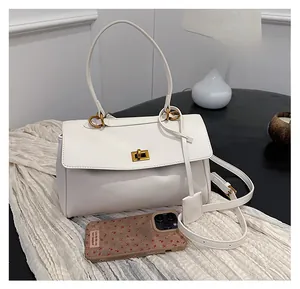 Size comparison of white leather handbag with golden lock next to an iPhone
