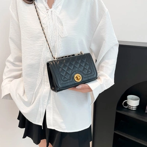 Classic black quilted crossbody bag with gold chain strap shown on model in white shirt