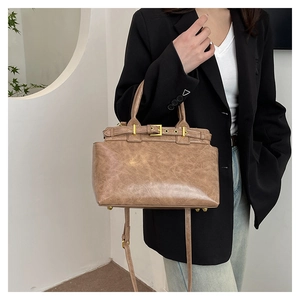 Detail of vintage brown leather tote bag with gold hardware and protective metal feet