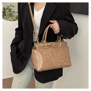 Detail of vintage brown leather tote bag featuring gold buckle and detachable shoulder strap