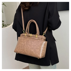 Side view of retro brown tote bag with metal buckle and detachable shoulder strap on model