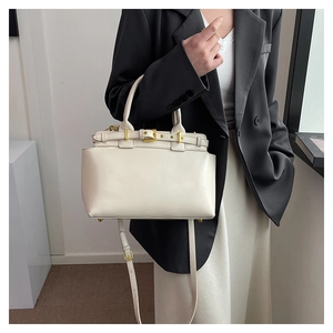 Detail of cream leather tote bag featuring gold hardware and protective base feet