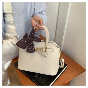 Detail of cream white leather tote bag with polka dot scarf and golden metal buckle