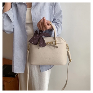 Detail of off-white lychee leather tote bag with silk scarf and gold metal hardware