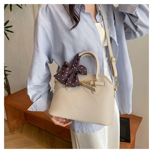 Close-up of beige lychee leather texture and silk scarf detail on the handbag strap