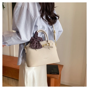 Detail of off-white lychee texture tote bag with brown polka dot silk scarf and gold lock