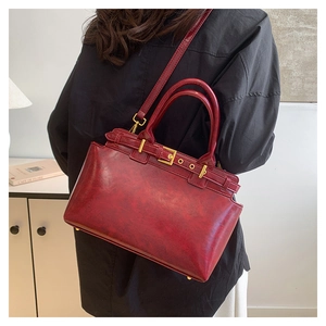 Detail of vintage dark red leather tote bag with gold metal buckle and detachable strap