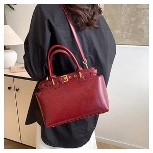 Detail of vintage burgundy leather tote with gold buckle and adjustable shoulder strap