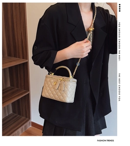 Detail of beige quilted mini vanity bag with gold handle and chain strap on model