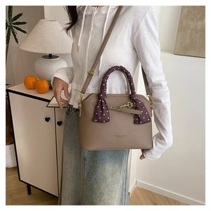Detail of brown lychee leather tote with gold hardware and purple polka dot silk scarf handle