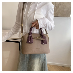 Detail of coffee brown pebble leather tote bag with silk scarf on handle and metal lock