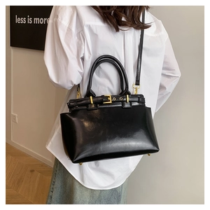 Detail of glossy black tote bag with gold hardware and adjustable shoulder strap