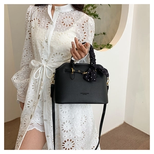 Detail of black lychee leather tote bag with polka dot scarf and golden hardware