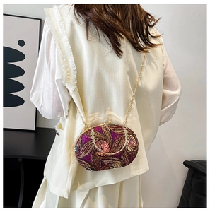 Pochette de soirée luxe à paillettes violettes avec chaîne dorée portée par un mannequin