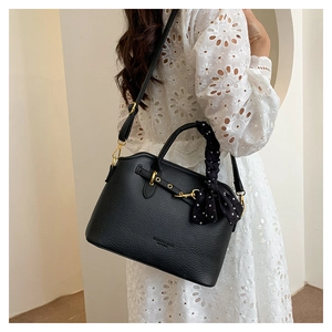 Close-up of black lychee leather tote with gold hardware and a polka dot silk scarf detail
