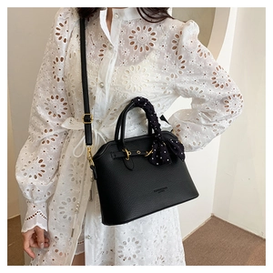 Detail of black lychee texture leather tote with polka dot scarf and gold metal hardware