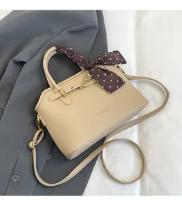 Detail of beige tote bag with litchi texture, silk scarf handle and metal gold hooks