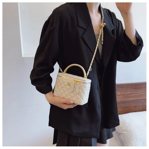 Close-up of beige quilted vanity bag featuring gold flower hardware and chain strap