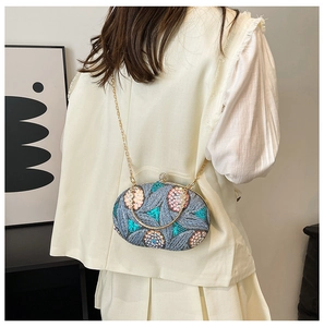 Détail de broderie florale à paillettes sur pochette de soirée avec anse métal