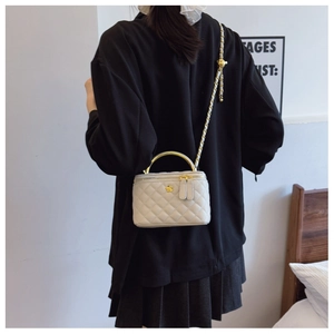Detail showing beige quilted crossbody bag with gold metal handle and chain strap