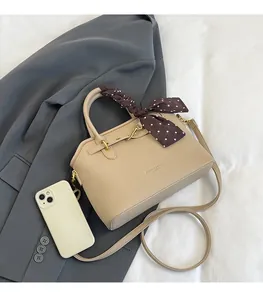 Detail of beige lychee grain tote bag with decorative polka dot scarf and golden hardware