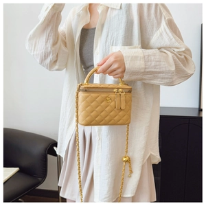 Detail of yellow quilted leather vanity case with golden camellia and chain strap