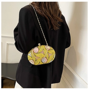 Détail de la pochette de soirée jaune à paillettes avec broderie florale et chaîne dorée