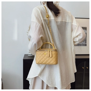Macro detail of quilted yellow chain box bag with golden floral metal clasp