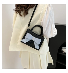 Detail of elegant black crossbody bag with light blue bow and heart-shaped metal buckle