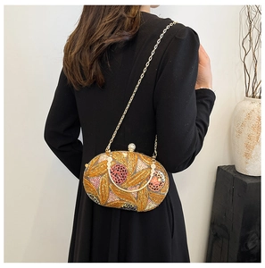 Détail d'une pochette de soirée à paillettes avec motifs floraux et fermoir perle sur mannequin