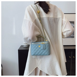 Detail of light blue quilted leather bag with gold chain strap and flower metal charm