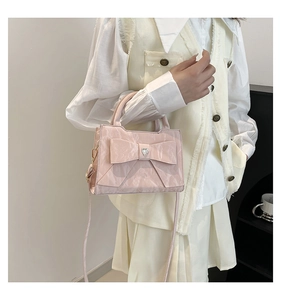 Detail of pink bow handbag with pleated texture and heart-shaped metal buckle detail
