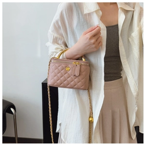 Detail of pink quilted box bag with golden camellia hardware and chain strap