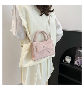 Close-up of light pink bow bag with heart rhinestone on cream vest and pleated skirt