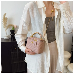 Detail of quilted pink box bag showing golden handle, metal ball adjuster, and chain strap