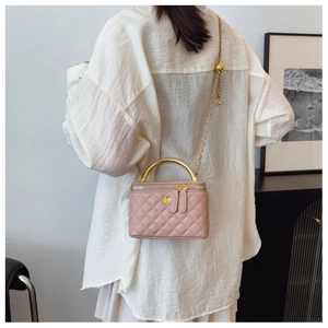 Rear view of model wearing pink quilted mini crossbody bag with gold chain and handle