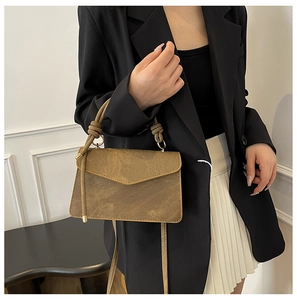 Detail of tan vintage leather crossbody bag with unique knotted handle and gold ring hardware
