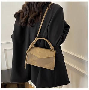 Rear view of a model wearing a vintage brown crossbody bag with a knot handle and V-flap