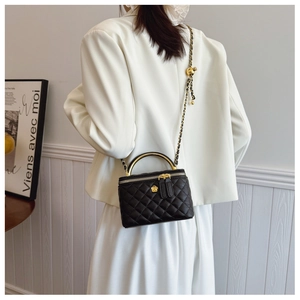 Detail of black quilted leather box bag with gold floral clasp and chain strap