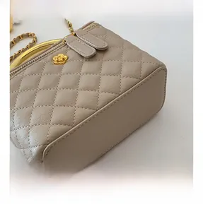 Detail of quilted beige bag with golden flower twist lock and metal handle chain
