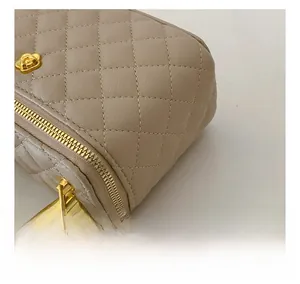 Macro detail of quilted beige leather handbag with gold zipper and camellia metal ornament
