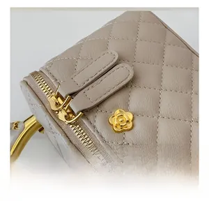 Close-up of quilted leather handbag with gold camellia charm and polished metal handle