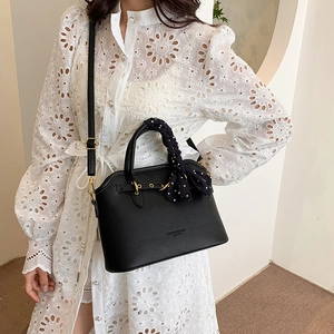 Retro black leather tote bag with polka dot scarf handle shown on a white lace dress model