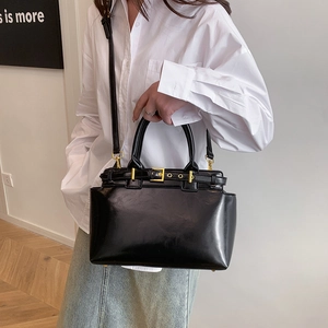 Classic black glossy tote bag with gold buckle detail and adjustable shoulder strap