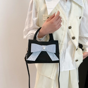 Black top handle bag with large cream bow and heart rhinestone on a chic model style