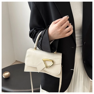 Detail of cream white leather crossbody bag with elegant gold D-shaped metal buckle
