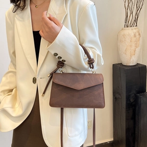 Vintage brown crossbody envelope bag with matte finish shown on a model in a white blazer